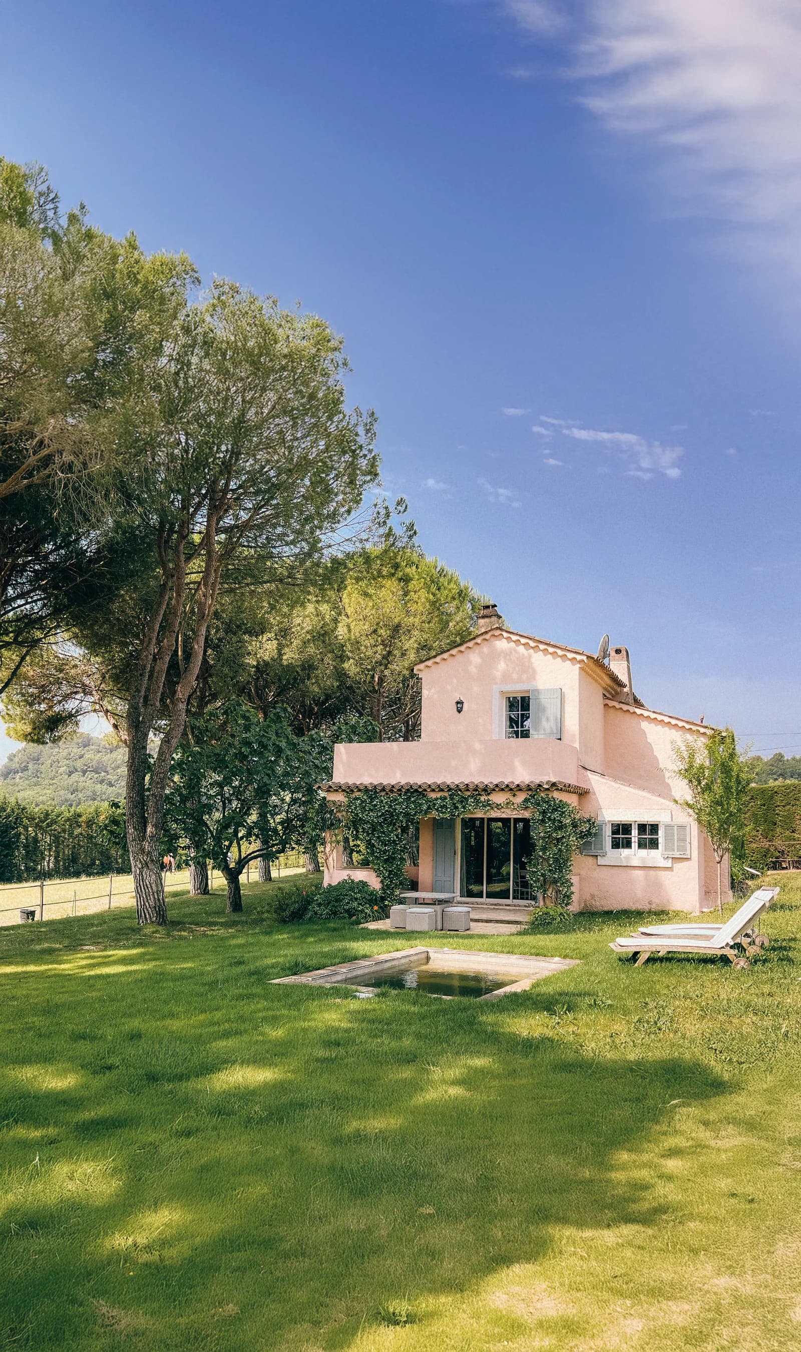 The pink Provençal house of Le Mas Rose with its lawn, pool and pine trees